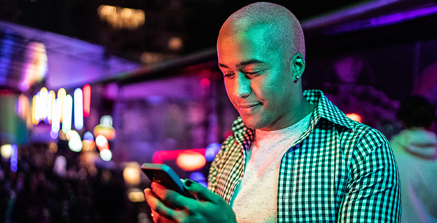 Man looking down at phone inside a club.