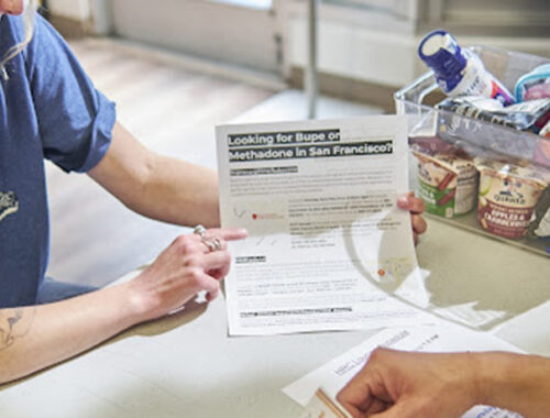 MAT coordinator holds a flier explaining drug treatment options.