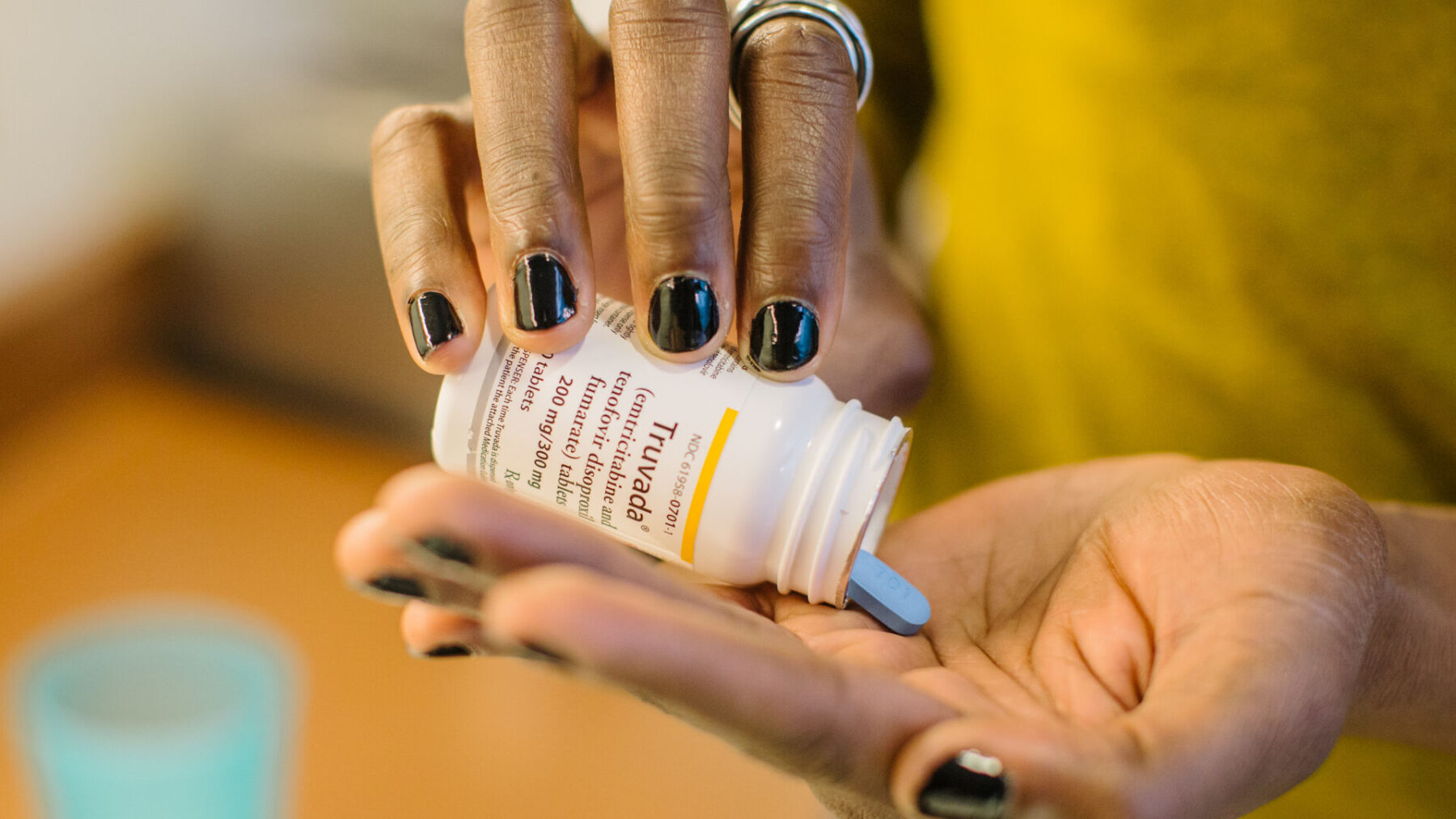 A person dispenses a blue pill from a medication bottle into their hand
